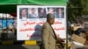 A protester walks past a poster with defaced pictures of Iraqi politicians and Arabic that reads, "Wanted by the Iraqi people for inciting against the demonstrators and for defacing the revolution's image," in Baghdad, Iraq, Dec. 28, 2019.