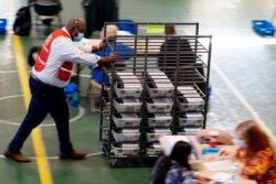 A Chester County election worker pushes mail-in and absentee ballots for the 2020 U.S. general election to be processed at West Chester University, in West Chester, Pennsylvania, Nov. 4, 2020.