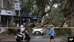 People walk past an area destroyed by the wind from Typhoon Kong-rey in Taipei, Taiwan, Nov. 1, 2024. 