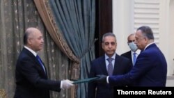 Iraq's President Barham Salih, left, instructs newly appointed Prime Minister Mustafa al-Kadhimi in Baghdad.