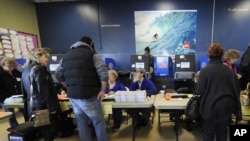 Voters sign in to vote at busy polling station at East Elementary School early Tuesday, November 6, 2012, in Long Beach, N.Y., one of several voting locations that were created as a result of Superstorm Sandy. 