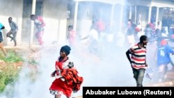 Des partisans de Bobi Wine fuient les gaz lacrymogènes lors d'un rassemblement de campagne près de Kampala, en Ouganda, le 30 novembre 2020.