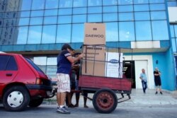 People load a trailer with a refrigerator and a washing machine just bought from a shop selling products for dollars in Havana, Oct. 28, 2019.