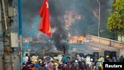 Anti-coup protesters take cover at a barricade as they clash with security forces on Bayint Naung Bridge in Mayangone, Yangon, Myanmar March 16, 2021. REUTERS/Stringer