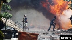 Rohingya men are seen among houses set on fire during fighting between Buddhist Rakhine and Muslim Rohingya communities in Sittwe, Burma, June 10, 2012.