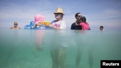 Retiree Madeline Barcelo (C) holds her granddaughter surrounded by relatives at the beach in Varadero, Cuba, Aug. 26, 2015. 