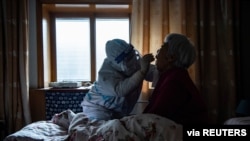 A medical worker collects a swab from a bedridden elderly at a house during the second round of citywide nucleic acid testing following a recent COVID-19 outbreak in Shijiazhuang, Hebei province, Jan. 13, 2021. (cnsphoto via Reuters)
