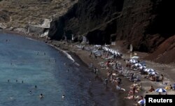 Turis berjemur di Pantai Merah di Pulau Santorini, Yunani, 2 Juli 2015. (Foto: Reuters)
