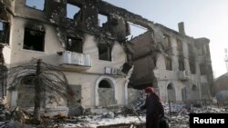 Wata mace take wucewa kusa da wani gini da aka lalata a garin Vuhlehirsk kusa da Donetsk, Ukraine.