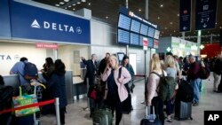Passengers wait in front of the desk of American airline company 'Delta', at the Roissy Charles de Gaulle airport, north of Paris, Thursday, March 12, 2020.