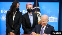 Margaret Purce dan Megan Rapinoe dari tim sepak bola putri AS, menyaksikan Presiden Joe Biden menandatangani deklarasi Hari Kesetaraan Gaji di Gedung Putih, Washington, Rabu, 24 Maret 2021. (Foto: Jonathan Ernst/Reuters)