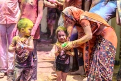 A mother teaches to her children to use water guns during Holi, the spring festival of colours, in Hyderabad on March 29, 2021.
