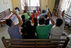 Myanmar nationals including those who said they are police and firemen and recently fled to India, flash the three-finger salute at an undisclosed location in India's northeastern state of Mizoram, near the border, March 15, 2021.