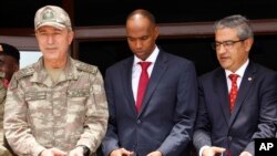 Le chef d’état-major turc, le général Hulusi Akar, à gauche, le Premier ministre somalien Hassan Ali Khayre, au centre, et l’ambassadeur turc en Somalie, Olgan Bekar, coupent le ruban inaugural du centre de formation militaire à Mogadiscio, Somalie, 30 se