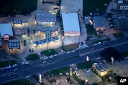 In this aerial photo, investigators work the shooting scene in Baton Rouge, La., where several law enforcement officers were either shot or killed, Sunday, July 17, 2016.