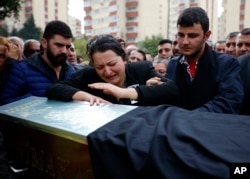 FILE - A relative cries over the coffin of Uygar Coskun, 32, killed in Saturday's bombing attacks, during his funeral, in Ankara, Turkey, Oct. 12, 2015.