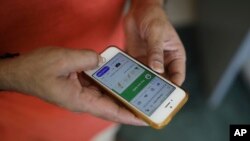 In this Thursday, May 7, 2020 photo, an Indian man uses Aarogya Setu app on his mobile phone in New Delhi, India. (AP Photo/Altaf Qadri)