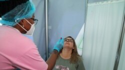 A healthcare worker collects a swab from Bronwen Cook for a PCR test against the coronavirus disease (COVID-19) before traveling to London, at O.R. Tambo International Airport in Johannesburg, South Africa, Nov. 26, 2021.