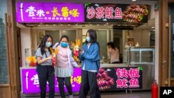 People wearing face masks to protect against the spread of the new coronavirus buy snacks at a shop on a pedestrian shopping street in Beijing, May 16, 2020. 