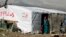 FILE - A woman stands outside her tent in a Syrian refugee camp in Houch al-Harimeh, Lebanon. Refugees in Syria’s neighboring countries often live in terrible conditions, spurring many to attempt the journey to Europe.
