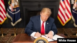 លោក​ប្រធានាធិបតី ដូណាល់ ត្រាំ ចុះ​ហត្ថលេខា​លើ​បទបញ្ជា​ស្តី​ពី​ការ​ដាក់​ទណ្ឌកម្ម​នៅ​ក្នុង​បន្ទប់​បៃតង ក្នុង​ក្រុង Bedminster Township រដ្ឋ New Jersey កាលពី​ថ្ងៃទី៥ ខែសីហា ឆ្នាំ២០១៨។