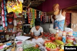 FILE - A man from the Rohingya community fills out an identification form provided by local police inside his shop at a camp in New Delhi, Oct. 4, 2018.