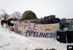 FILE - Hay is stacked up to feed horses at a protest encampment along the route of the Dakota Access oil pipeline near Cannon Ball in southern North Dakota, Jan. 24, 2017.