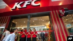 Staff members greet visitors at its grand openning, first branch of Kentucky fried chicken (KFC) restaurant, June 30, 2015, in Yangon, Myanmar.