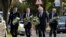 British Prime Minister Boris Johnson and leader of the Labour Party Keir Starmer, second from left, carry flowers as they arrive at the scene where member of parliament David Amess was stabbed Friday, in Leigh-on-Sea, Essex, England, Oct. 16, 2021. 