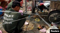Thai police officers inspect the site of an explosion scene during an anti-government protest at Khao Saming district, Trat province, Feb. 23, 2014. 