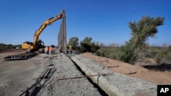 Government contractors erect a section of border wall along the Colorado River, Sept. 10, 2019 in Yuma, Ariz. Construction began as federal officials revealed a list of Defense Department projects to be cut to pay for the wall.