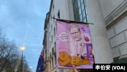 港人Moses Ng举起讽刺习近平和工党首相的漫画，表达对英国工党政府对华政策的失望。（李伯安/美国之音）