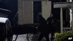 A body is removed from Gold Spa massage parlor after a shooting, late March 16, 2021, in Atlanta, Georgia. 
