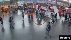 Potongan gambar CCTV menunjukkan pria yang diduga Kim Jong-nam (dilingkari merah) berbicara dengan petugas bandara setelah dihadang perempuan berkaos putih, di Bandar Udara Internasional Kuala Lumpur (13/2).