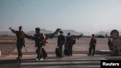 A U.S. Marine assigned to the 24th Marine Expeditionary Unit (MEU) escorts Department of State personnel to be processed for evacuation at Hamid Karzai International Airport, Kabul, Afghanistan, August 15, 2021. Picture taken August 15, 2021. U.S. Marine Corps/Sgt. Isaiah Campbel