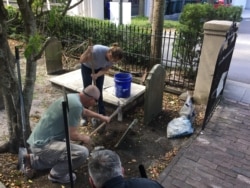 American College of the Building Arts student Leigh Yarbrough and her instructor Simeon Warren restore a tombstone, Charleston, S.C., Sept. 17, 2019. (J. Taboh/VOA News)