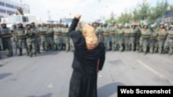 资料照：一名新疆维吾尔妇女举拳向一队中国武警士兵表示抗议。(照片来自世界维吾尔代表大会网站)