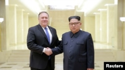 Pemimpin Korea Utara Kim Jong-un bersalaman dengan Menteri Luar Negeri AS Mike Pompeo pada foto yang dirilis oleh kantor berita Korea Utara (KCNA) pada 9 Mei 2018.