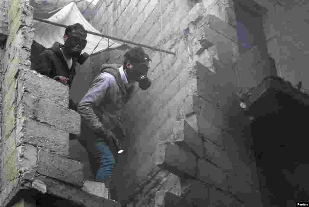 Residents wear masks as they search for bodies after shelling by forces loyal to Syria's President Bashar al-Assad, al-Ansari, Aleppo, Syria, January 3, 2013