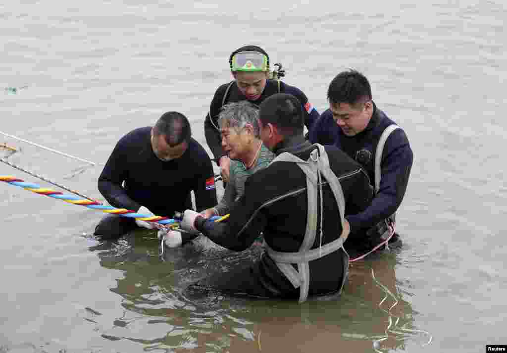 A woman is helped by divers from a sunken ship in Jianli, Hubei province, China, June 2, 2015. Divers pulled the 65-year-old woman from the hull of the passenger ship carrying 458 people that capsized on China&#39;s Yangtze River and others could still be alive, state media said on Tuesday.