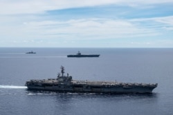 Dalam foto ini disediakan oleh US Navy, USS Ronald Reagan (CVN 76, depan) dan USS Nimitz (CVN 68, belakang) Carrier Strike Group berlayar bersama dalam formasi, di Laut Cina Selatan, Senin, 6 Juli 2020. (Foto : AP)
