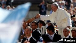Pope Francis greets people as he arrives to lead his Wednesday general audience in Saint Peter's square at the Vatican, Sept. 18, 2013.
