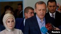 Presiden Tayyip Erdogan (kanan) dan istrinya, Emine Erdogan, berbicara kepada media setelah memberikan suara di sebuah TPS di Istanbul, Minggu (1/11). 