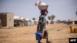 FILE - A woman walks at the Goudebo refugee camp for Malian refugees in Dori, Burkina Faso, Feb. 3, 2020. More than 8 000 Malian refugees live in in the Goudebo refugee camp.
