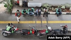 Pengemudi layanan ojek Gojek dan Grab enunggu penumpang di Jakarta pada 24 Juni 2020. (Foto: AFP/Adek Berry)