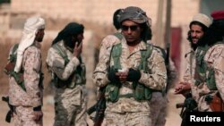FILE - A Syrian Democratic Forces (SDF) fighter uses a mobile phone as he stands with fellow fighters in the town of Hisha, Syria, after they took control of the area from Islamic State militants, Nov. 14, 2016. The Pentagon sees the SDF as an effective fighting force against IS militants. 