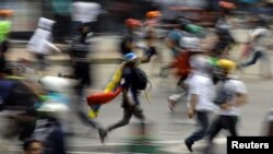 Demonstrators run during clashes with riot security forces at a protest against Venezuelan President Nicolas Maduro's government, in Caracas, Venezuela, May 30, 2017. 