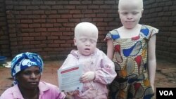 Une femme pose avec ses deux enfants albinos au Malawi. (L. Masina/VOA)