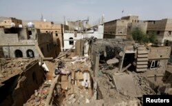 People check damage at the site of an airstrike in Amran, Yemen, June 25, 2018.