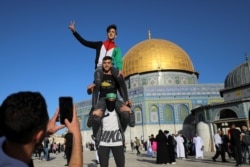 Pemuda Palestina berpose dengan Kubah Batu terlihat di latar belakang, saat shalat Idulfitri di kompleks Masjid al-Aqsa di Kota Tua Yerusalem, di tengah pertempuran Israel-Gaza, 13 Mei 2021. (Photo: REUTERS/Ammar Awad)